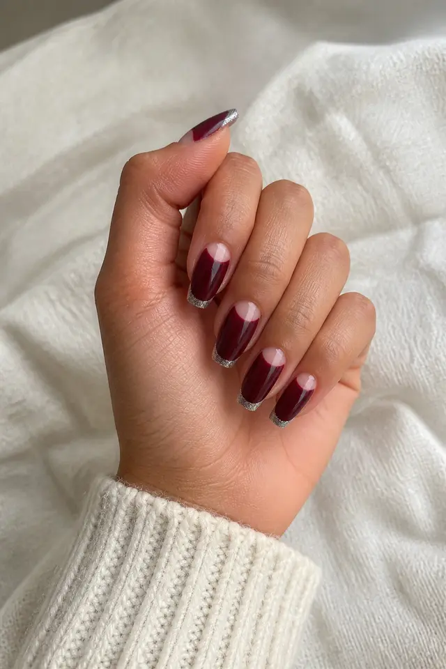 Silver and burgundy half-moon nails on medium ballerina tips with light skin and a softly curled thumb pose in natural daylight