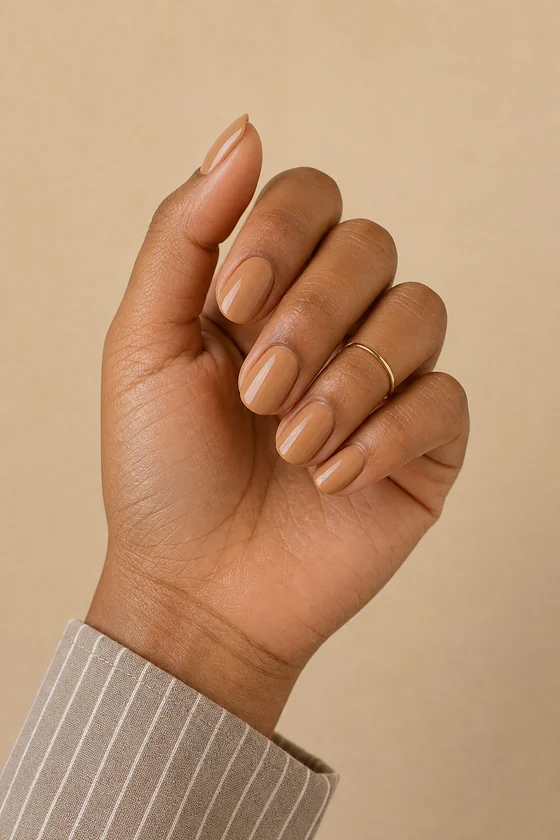 Tan skin hand in a three-quarter curled pose wearing latte nude almond nails with a subtle beige-to-coffee gradient