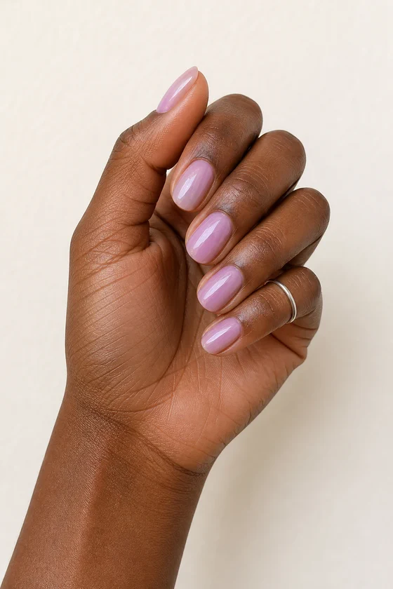 Rich dark brown skin hand in a soft curled pose wearing short glossy lavender-pink oval nails with one tiny plain silver band